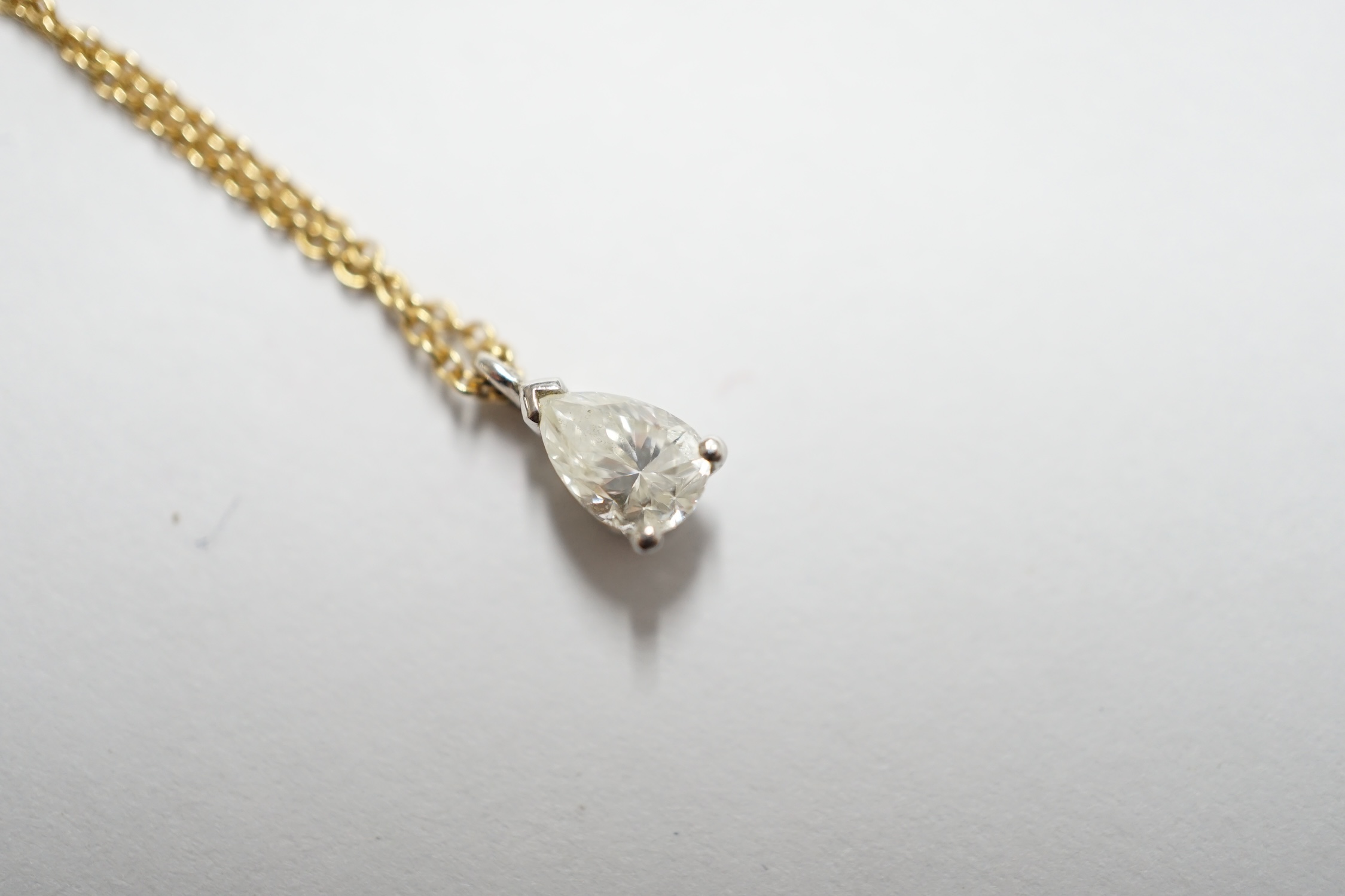 A white metal and pear shaped diamond set pendant, overall 7mm, on a fine link 18ct gold necklet, in a Tiffany & Co box. Condition - good